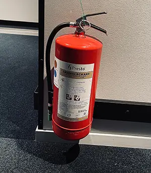 Bättre brandskydd med brandsläckare - bild på röd brandsläckare hängandes på vägg